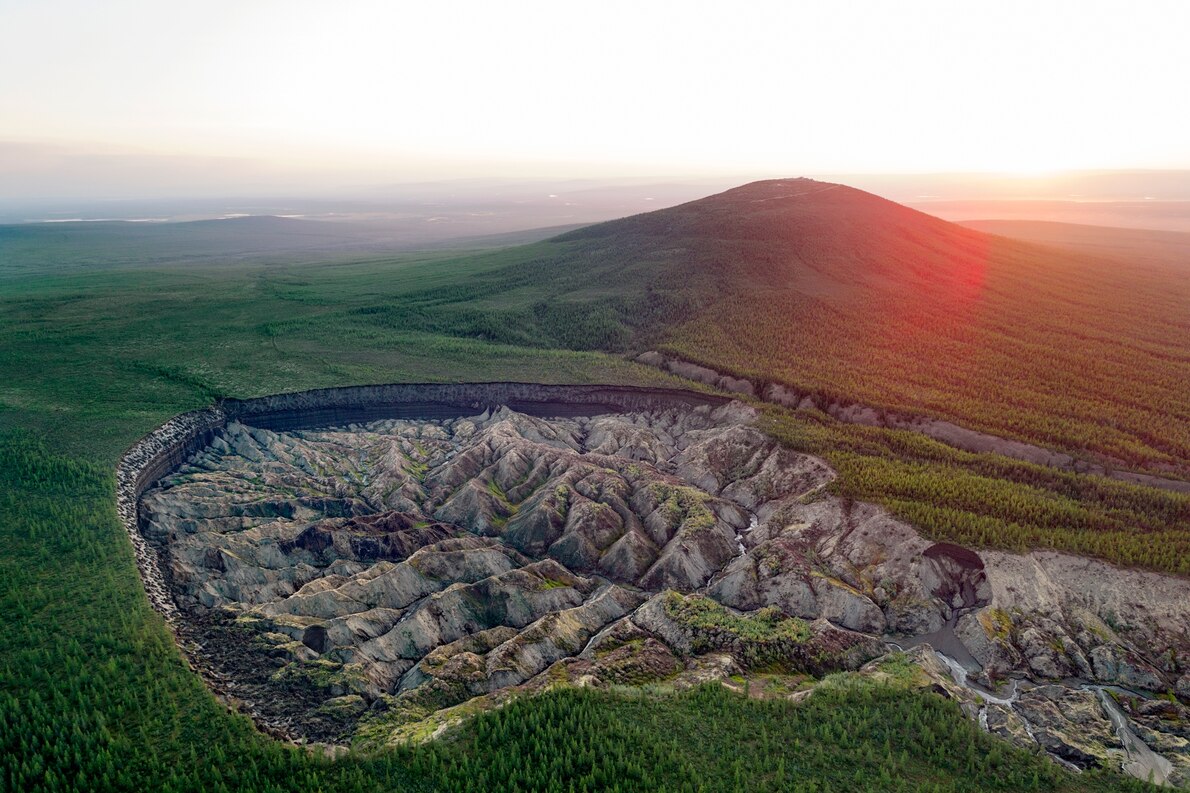 ロシア、シベリア東部にあるバタガイカ・クレーターは、気候変動によって永久凍土が解け、地盤が沈下してできた穴で最大のものだ。直径800メートルで、今も成長し続けている。北極圏には、他にも同じようにしてできたクレーターや湖がいくつもある。（PHOTOGRAPH BY KATIE ORLINSKY, NAT GEO IMAGE COLLECTION）