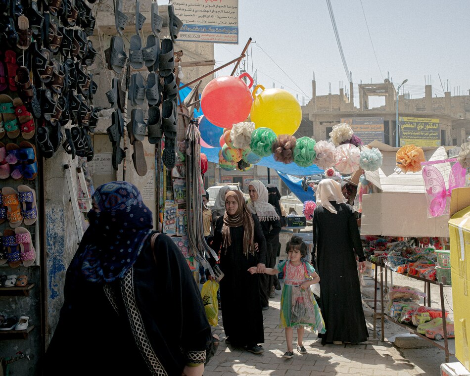 ラッカの中央市場で買いものをするシリアの女性たち。2021年5月に撮影。ISの支配下では、女性が外出するには、全身を隠して男性が付き添わなければならなかった。（PHOTOGRAPH BY WILLIAM KEO）