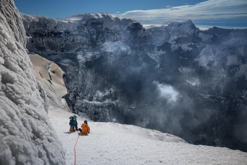 溶岩湖を確認するため、マイケル山の火口を下りて観察するニコルソンと火山学者のジョアン・ラジェス。火口の切り立った壁と火山灰の層は、過去の噴火を物語るとニコルソンは言う。「今より激しい爆発が起きていたことは、間違いありません」(PHOTOGRAPH BY RENAN OZTURK)