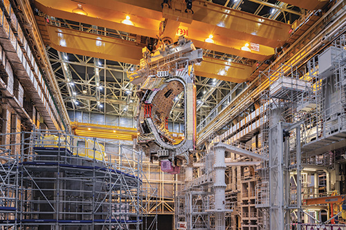 フランスのサン゠ポール゠レ゠デュランスにある高さ60メートルの建屋内で、ITER（国際熱核融合実験炉）の一部がクレーンでつり上げられる。この国際プロジェクトの目標は核融合技術を活用し、世界のエネルギー危機を解決することだ。（PHOTOGRAPH BY PAOLO VERZONE）