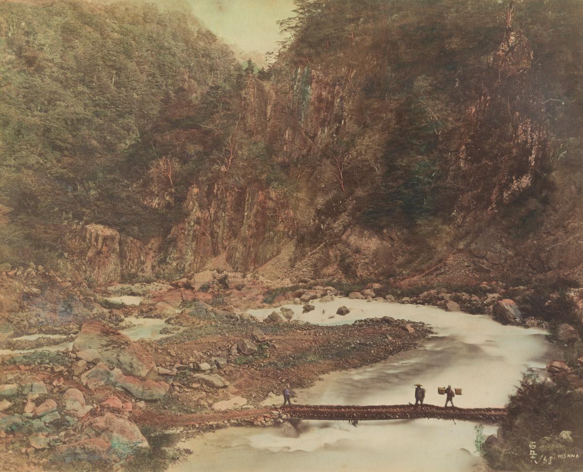 深山の川を渡る3人。右端の人は棒の両端に行李（こうり）を掛けて担ぐ、江戸時代のスタイルだ。 写真：PHELPS COLLECTION, NATIONAL GEOGRAPHIC SOCIETY ARCHIVES、撮影者不明、手彩色